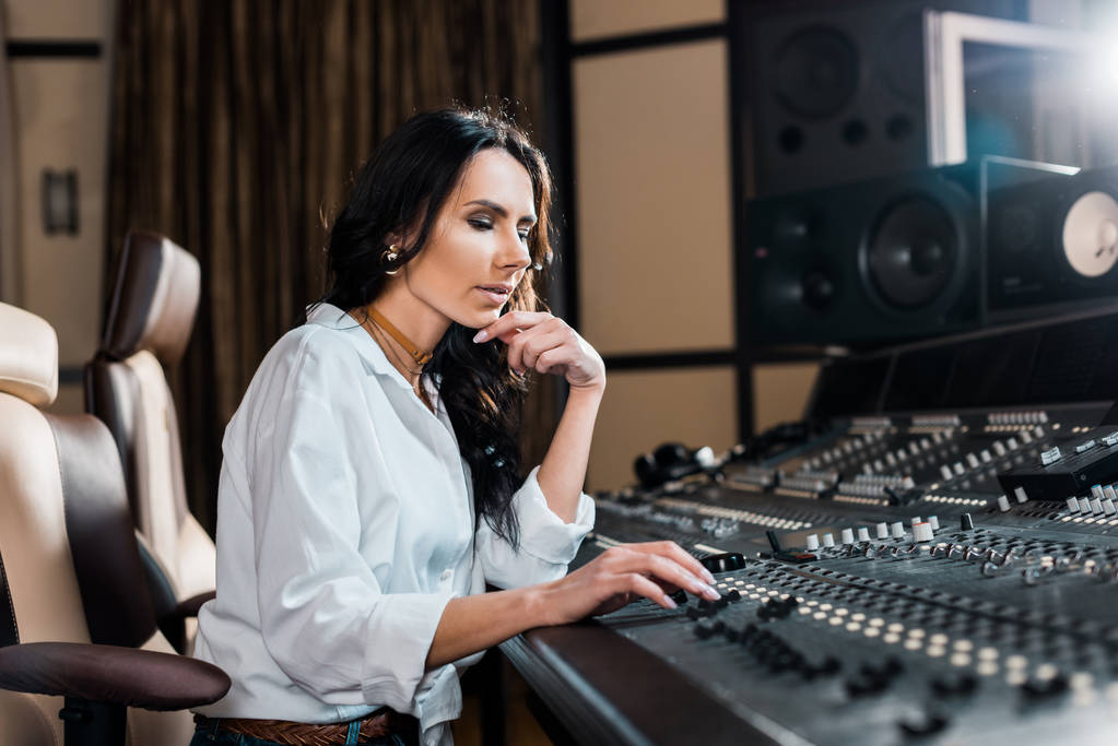 beautiful concentrated sound producer working at mixing console in recording studio - Photo, Image