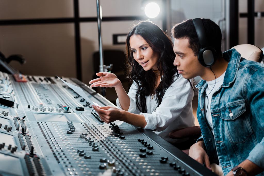due giovani produttori multiculturali di suoni che lavorano alla console di mixaggio in studio di registrazione
 - Foto, immagini