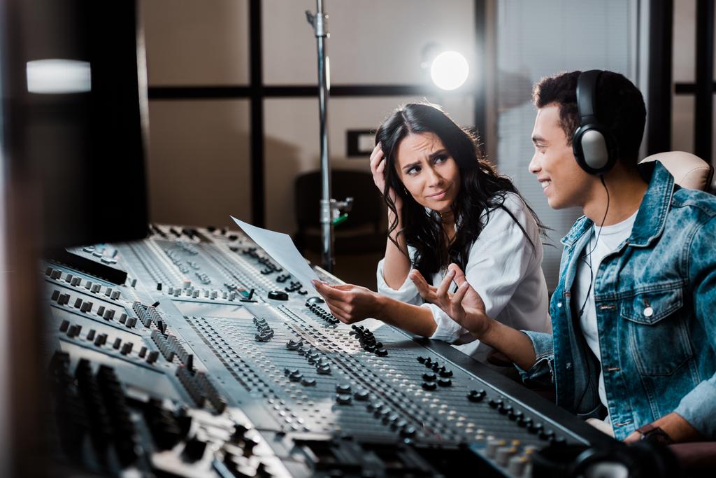 two sound producers talking while working at mixing console in recording studio - Photo, Image