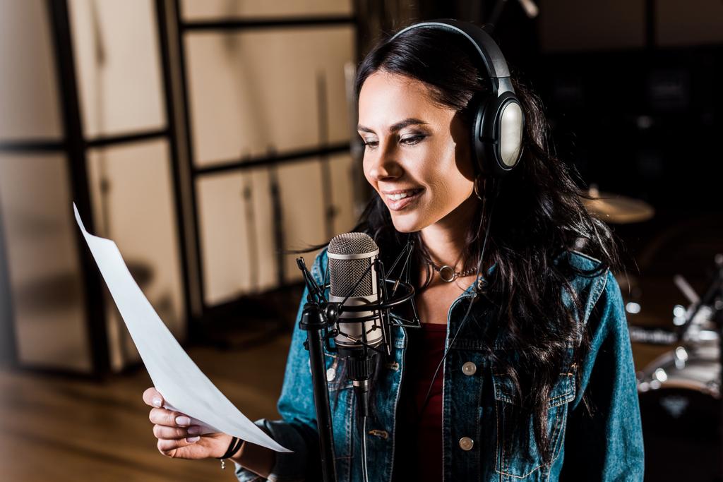 pretty woman in headphones singing in recording studio near microphone - Photo, Image