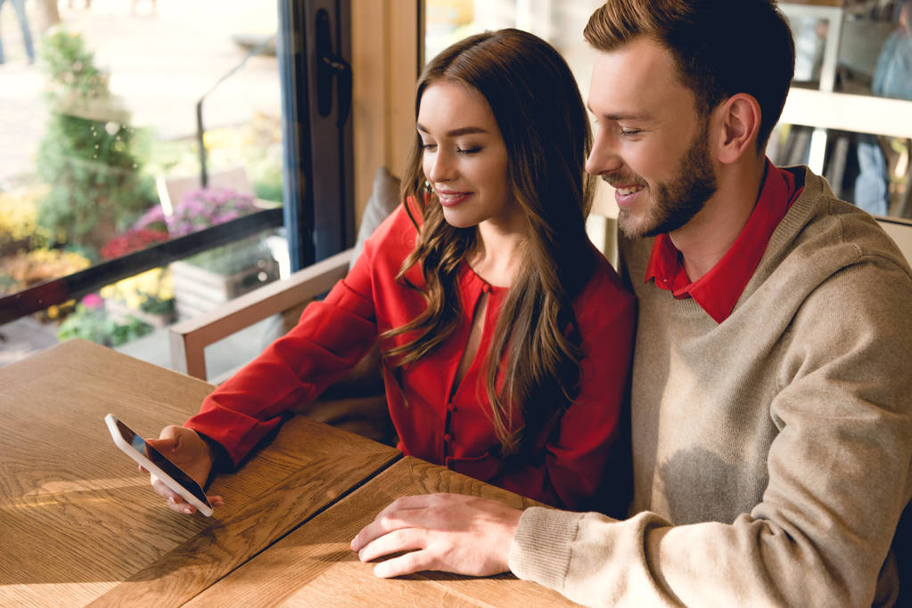 happy bearded man looking at smartphone near attractive girl in cafe  - Photo, Image