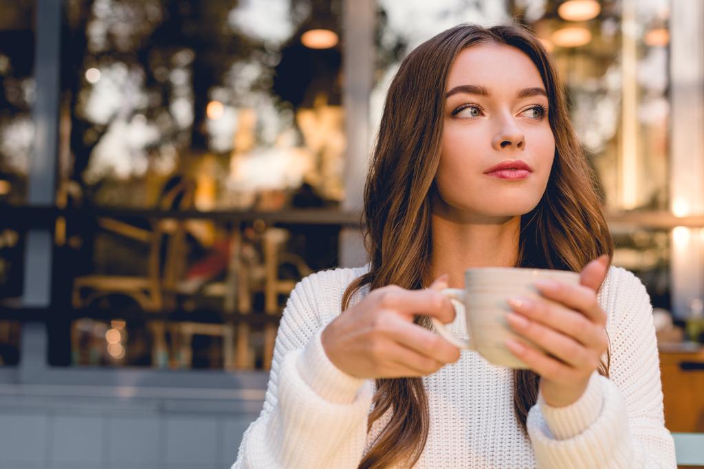 hermosa mujer joven sosteniendo la taza con café en la cafetería
  - Foto, Imagen
