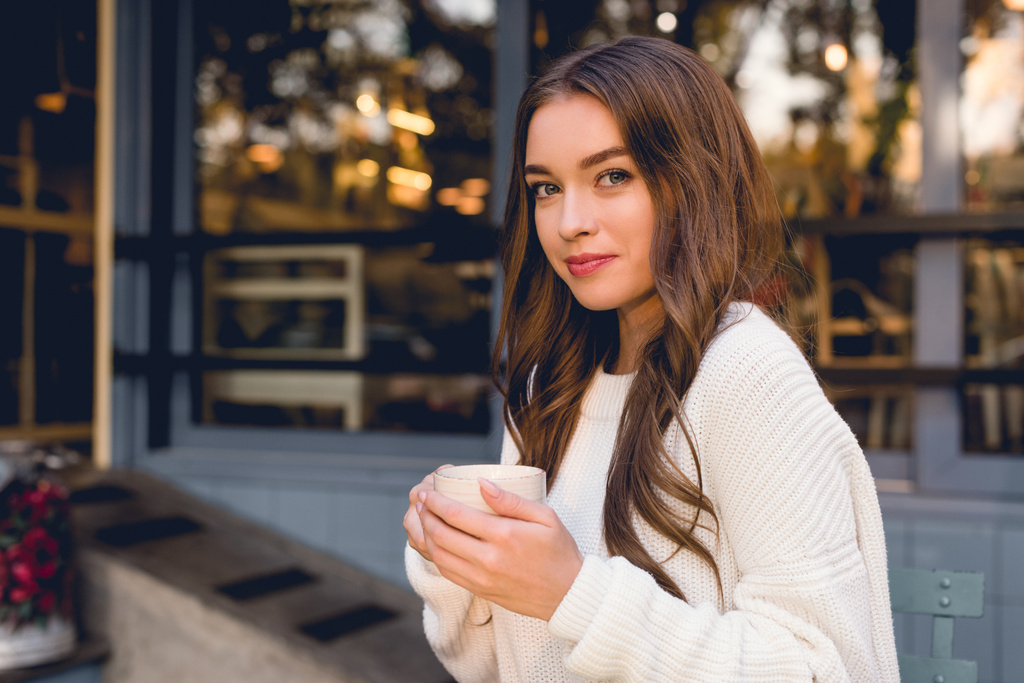 attractive young woman holding cup with coffee in cafe  - Photo, Image