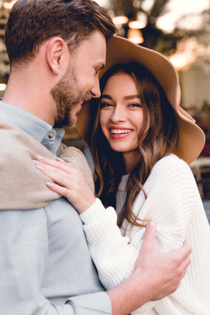 cheerful young woman in hat hugging happy boyfriend  - Photo, Image
