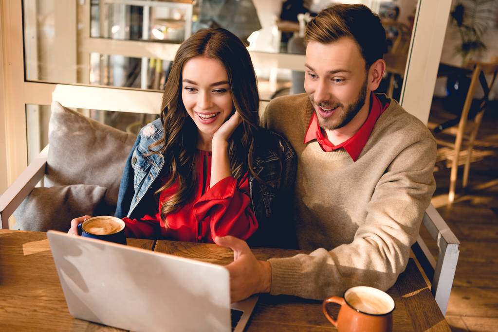 веселий чоловік і щаслива молода жінка дивиться на ноутбук в кафе
  - Фото, зображення