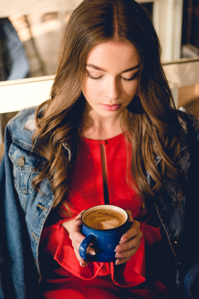 εναέρια θέα της όμορφης νεαρής γυναίκας κρατώντας φλιτζάνι καφέ στο καφέ  - Φωτογραφία, εικόνα