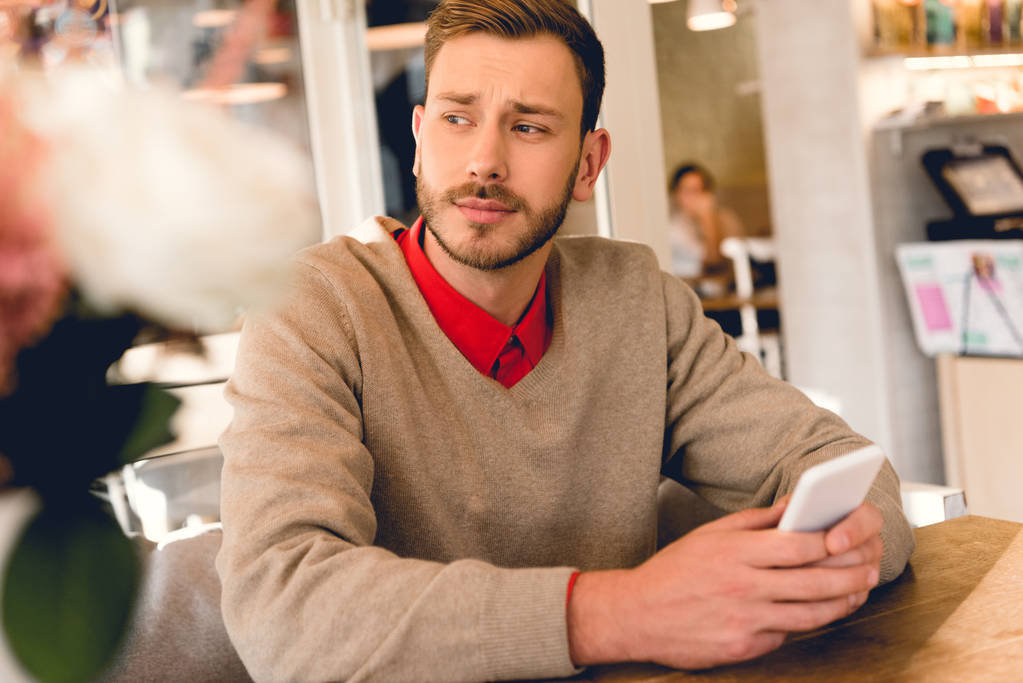 handsome bearded man holding smartphone in cafe  - Photo, Image