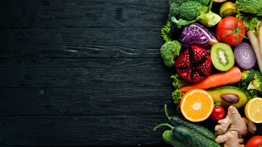 Verse groenten en fruit. Biologisch voedsel op een zwarte houten achtergrond. Bovenaanzicht. Gratis exemplaar ruimte. - Foto, afbeelding