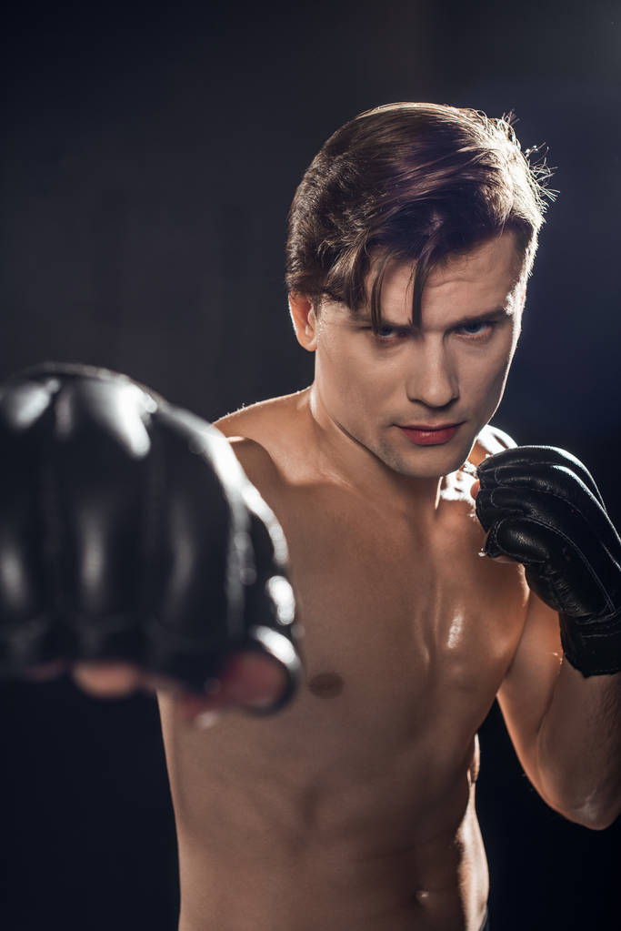 Selective focus of concentrated boxer in boxing gloves training and looking at camera - Photo, Image