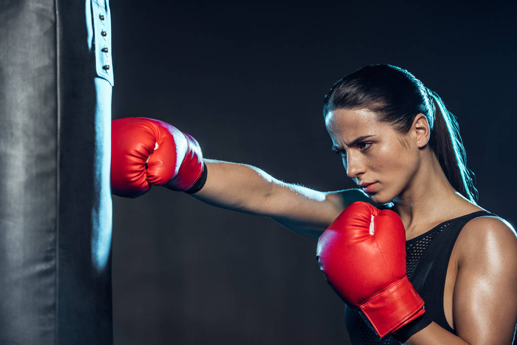 Втомився боксер у тренуванні червоних боксерських рукавичок з ударною сумкою на чорному
 - Фото, зображення