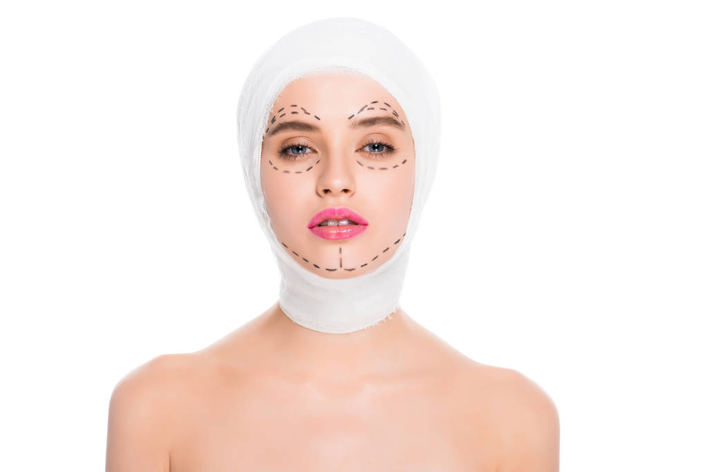 aantrekkelijke naakt jonge vrouw met verbonden hoofd en merken op het gezicht geïsoleerd op wit  - Foto, afbeelding