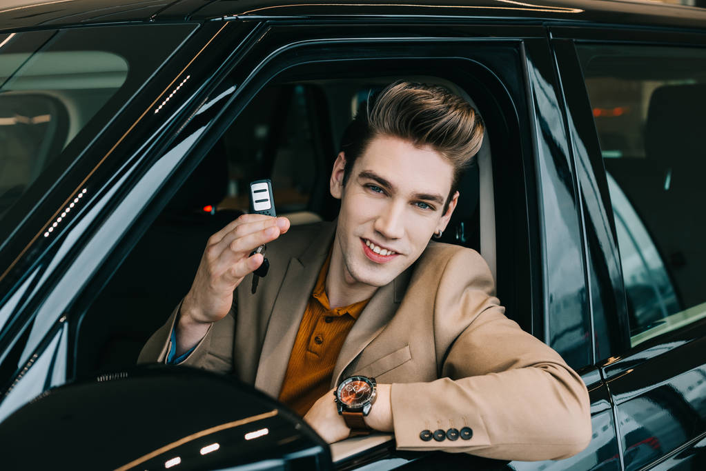 Kamera bakarken neşeli adam otomobil oturan ve araba anahtarı tutarak  - Fotoğraf, Görsel