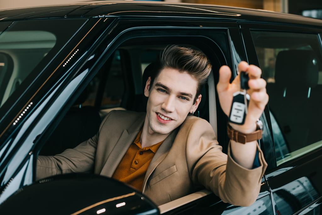 вибірковий фокус щасливого чоловіка, який тримає ключ від автомобіля, сидячи в автомобілі
  - Фото, зображення