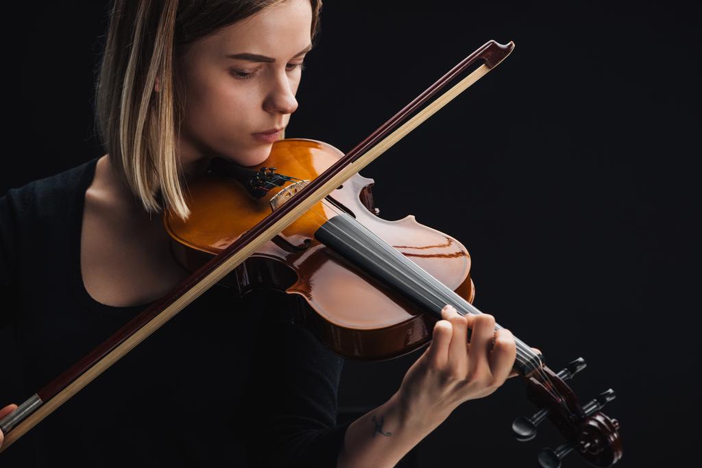 молодая сконцентрированная женщина играет на виолончели с луком, изолированным на черном
 - Фото, изображение