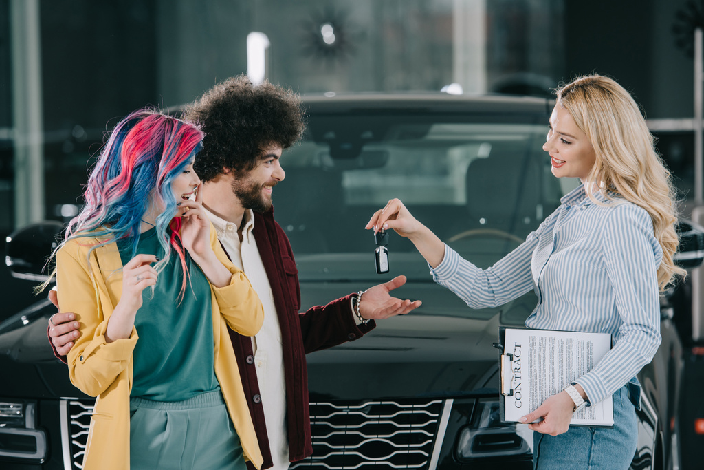 atractivo concesionario de coches rubios dando la clave para el hombre y la mujer feliz
  - Foto, Imagen