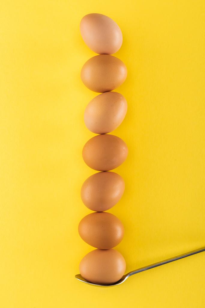 sept œufs de poulet brun sur cuillère sur fond jaune
 - Photo, image