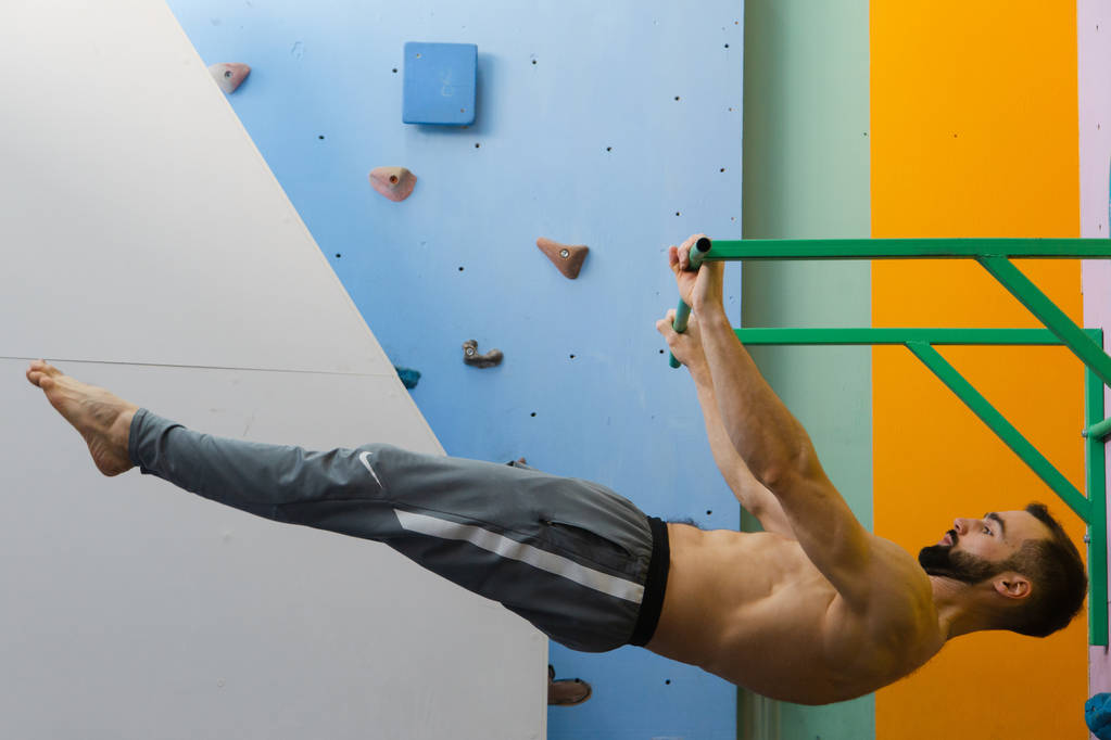 Vücut geliştiren adam spor salonundaki yatay çıtayı yükselterek egzersiz yapıyor. - Fotoğraf, Görsel
