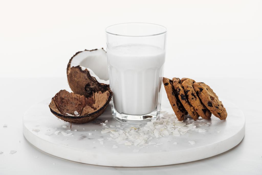 coconut vegan milk in glass near coconut and chocolate cookies isolated on white - Photo, Image