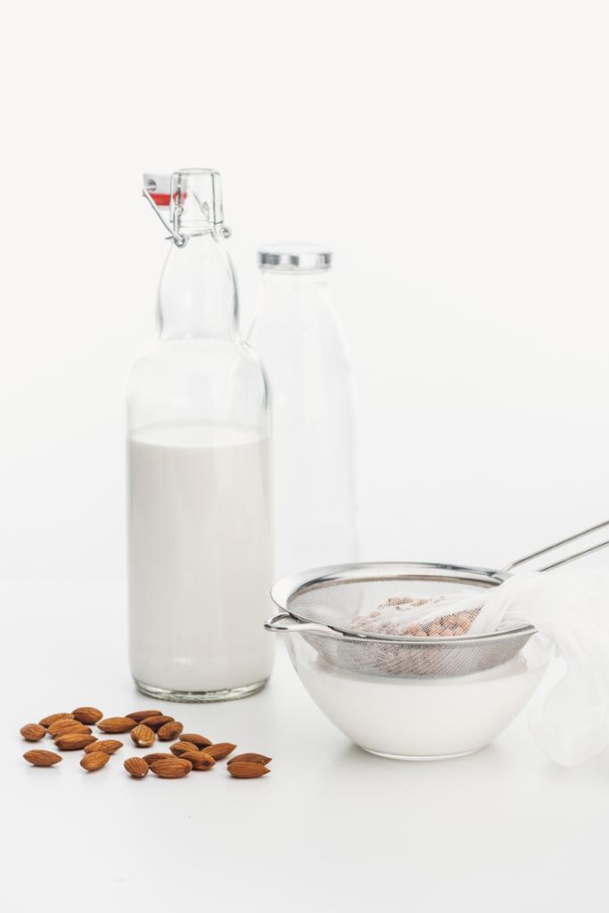 amêndoa e grão de bico leite vegan na tigela e garrafa perto de ingredientes
 - Foto, Imagem
