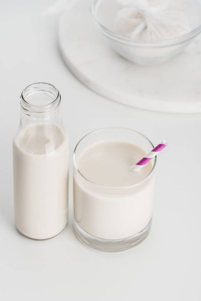 селективный фокус рисового молока в бутылке и стакане с рисом на фоне сыра
 - Фото, изображение