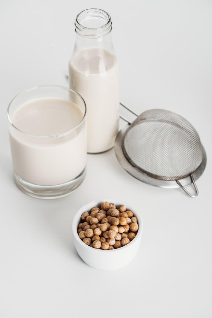 chickpea in bowl near vegan chickpea milk and sieve on grey background - Photo, Image