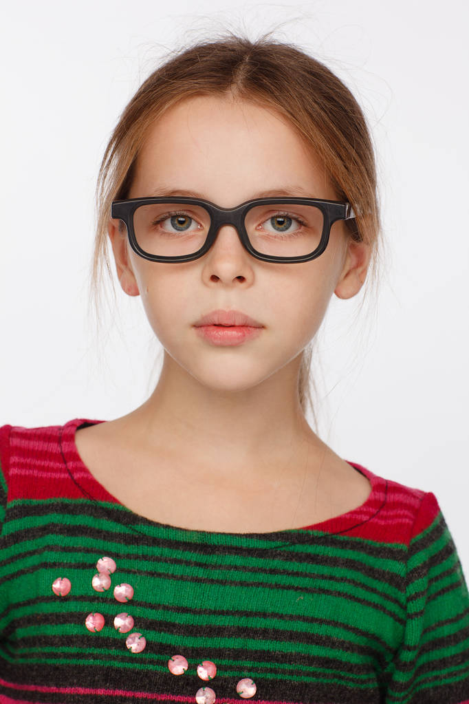Portret van 8-jarig meisje in een bril en een trui in een karmozijnrode en groene strepen. Studio fotosessie - Foto, afbeelding