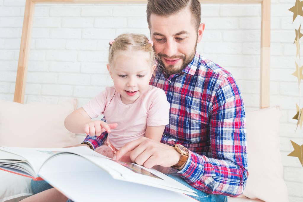Dad and daughter sit together and read a book. - Photo, Image