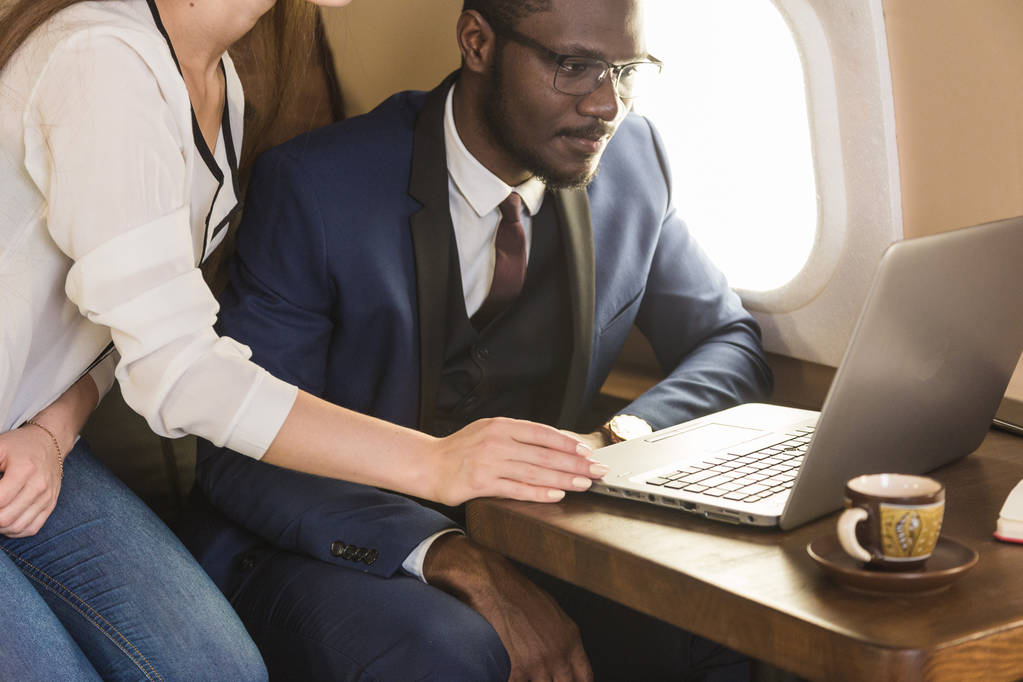 Joven empresario afroamericano exitoso con gafas y una atractiva compañera rubia en un jet privado. Servicio y vuelo de primera clase
 - Foto, imagen