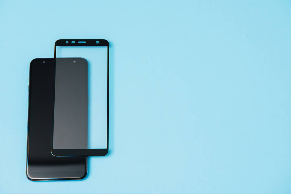 Teléfono inteligente con escudo de vidrio templado, pantalla de película cubierta .protector conceptos ideas. fondo azul
 - Foto, imagen