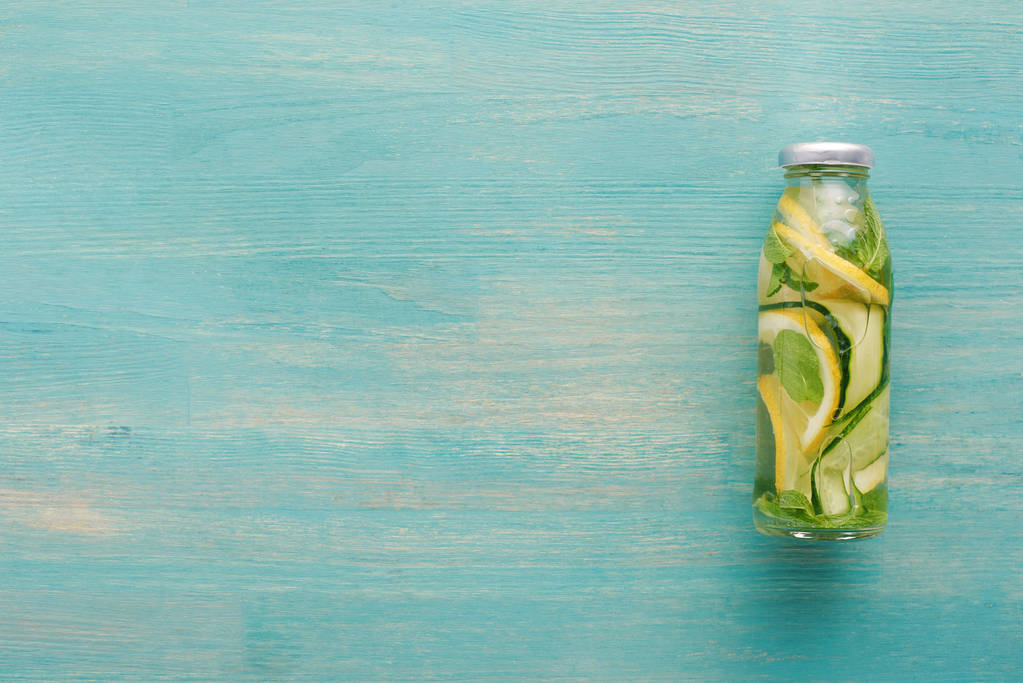 vista superior de la bebida de desintoxicación en botella con rodajas de limón y pepino fresco y menta
  - Foto, Imagen