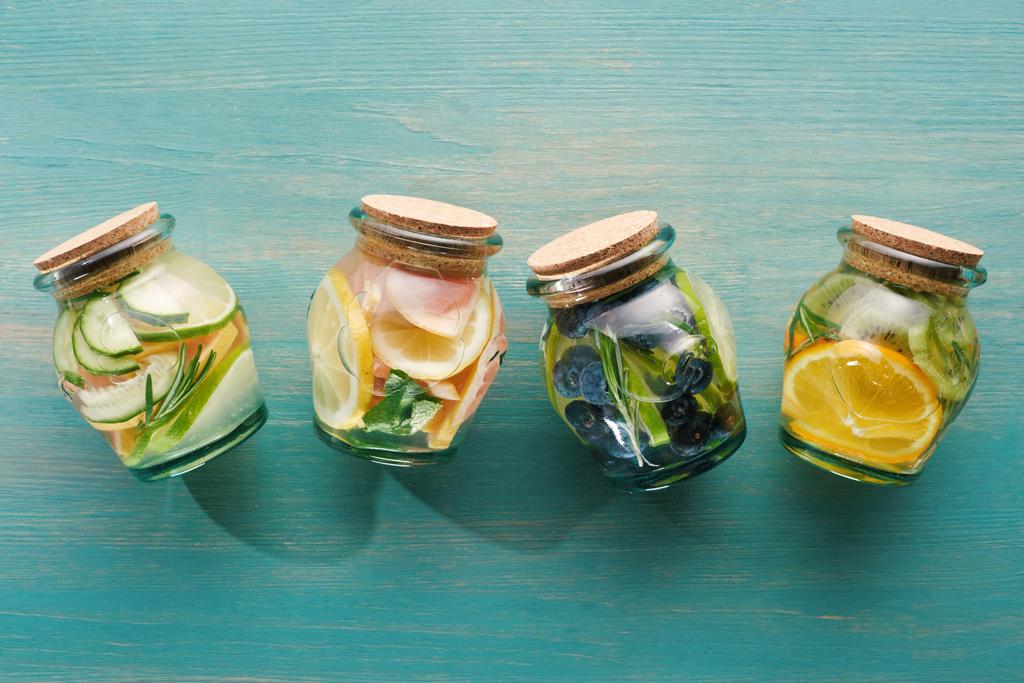 top view of detox drinks in jars with citrus fruits on blue wooden surface - Photo, Image