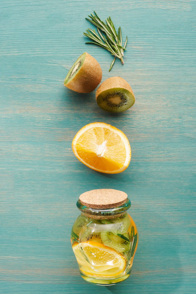 vista dall'alto della bevanda disintossicante in vaso con arance, kiwi e rosmarino
 - Foto, immagini