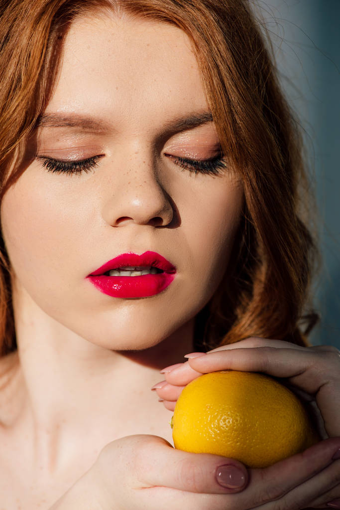 piękny zmysłowy rudowłosy dziewczyna z czerwonymi ustami stwarzających z cytryną - Zdjęcie, obraz