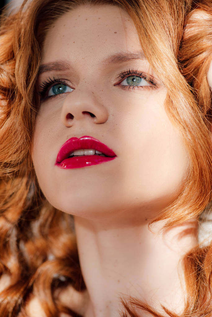Porträt einer schönen jungen rothaarigen Frau mit roten Lippen, die nach oben schaut - Foto, Bild