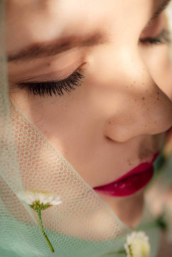 selective focus of beautiful young woman with eyes closed covered in veil with flowers - Photo, Image