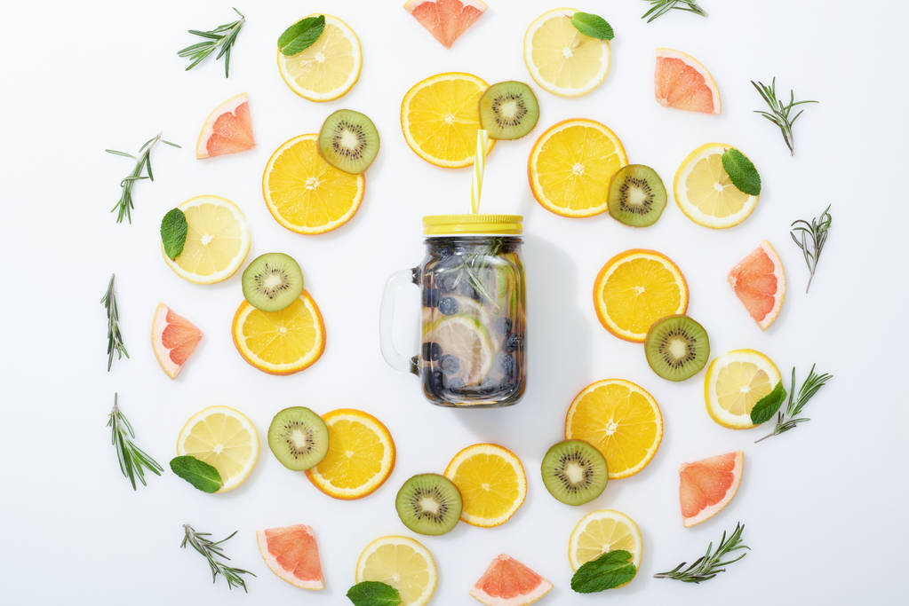 tasainen lay viipaloitu kiivi, appelsiinit, sitruunat, greippi, minttu, rosmariini ja detox juoma purkissa harmaalla pohjalla
 - Valokuva, kuva