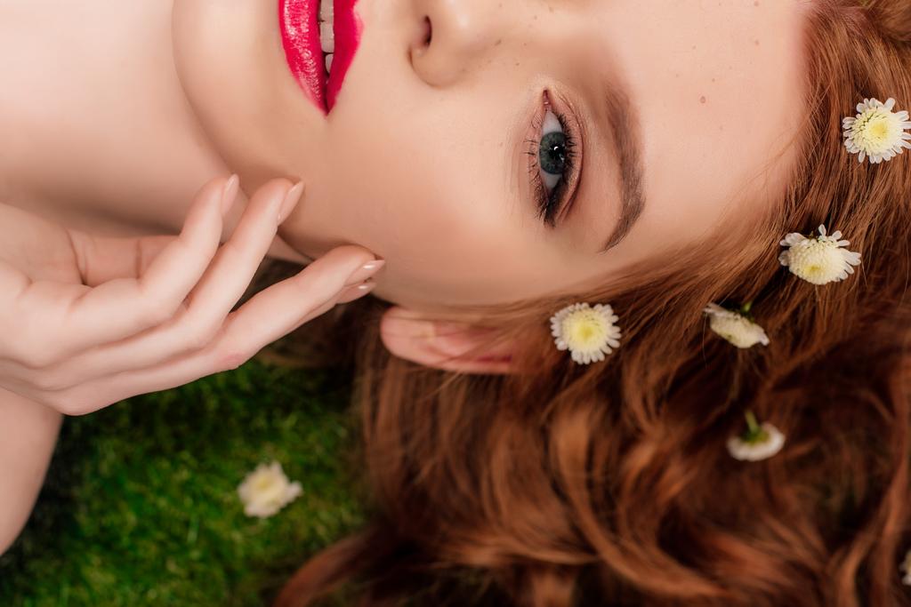 cropped view of beautiful young redhead woman with red lips and chrysanthemum flowers in hair  - Photo, Image
