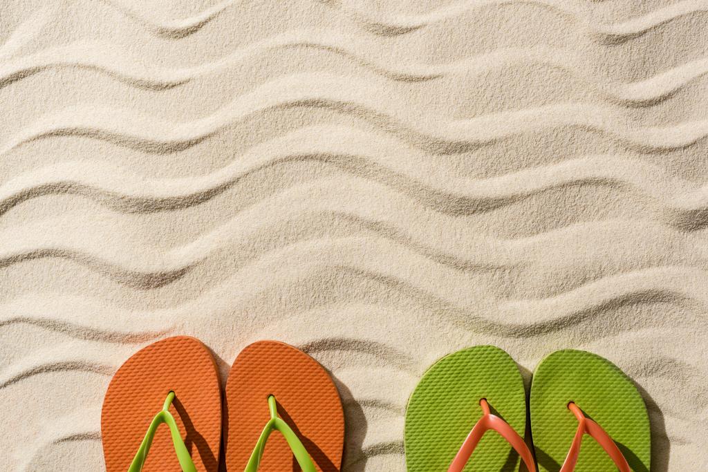 bovenaanzicht van kleurrijke flip flops op golvend zand met kopieerruimte - Foto, afbeelding