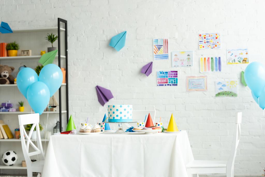 Slavnostní dort a party na stole v pokoji dekorované na oslavu narozenin s leteckými balóny - Fotografie, Obrázek