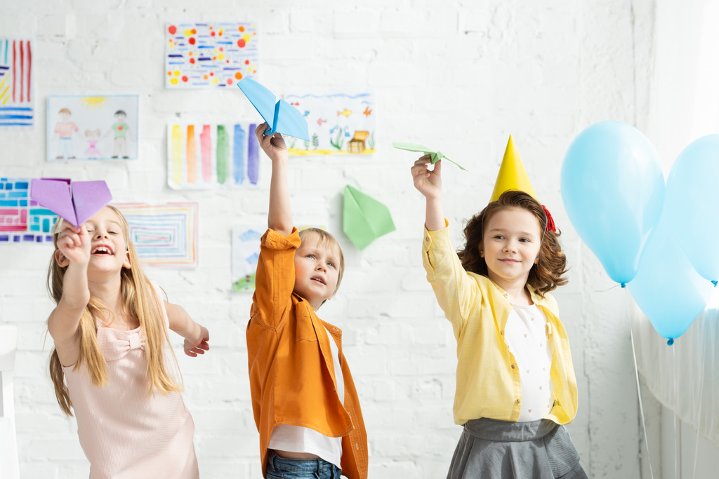 urocze dzieci bawiące się papierowe samoloty podczas przyjęcia urodzinowego w domu - Zdjęcie, obraz
