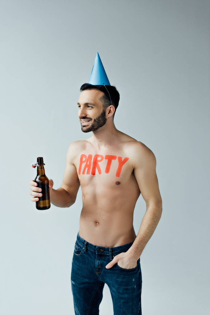 Mann mit Partymütze hält Bier in der Hand und blickt vereinzelt auf grau - Foto, Bild
