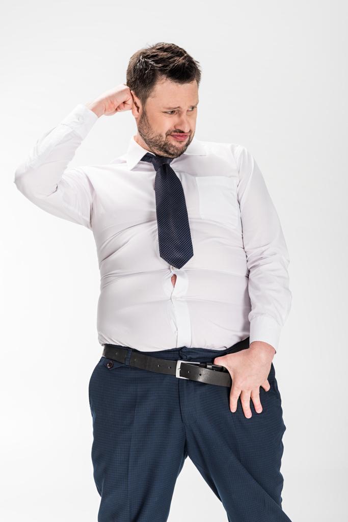 Übergewichtiger Mann in enger formaler Kleidung mit Hand am Gürtel posiert isoliert auf weißem Grund - Foto, Bild