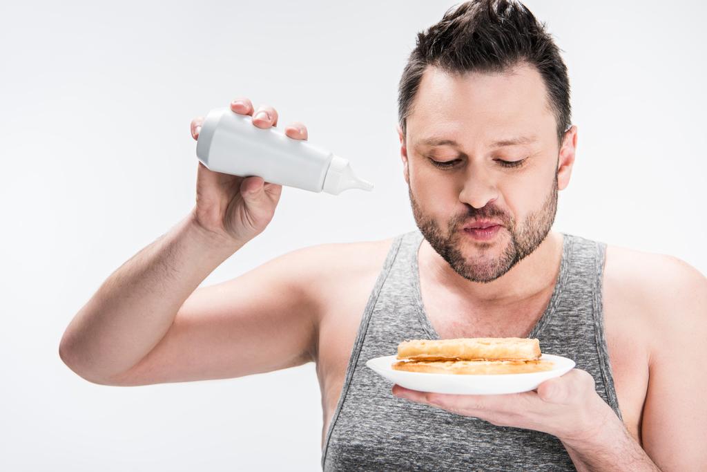 mollige man houdt fles siroop en wafels op wit - Foto, afbeelding