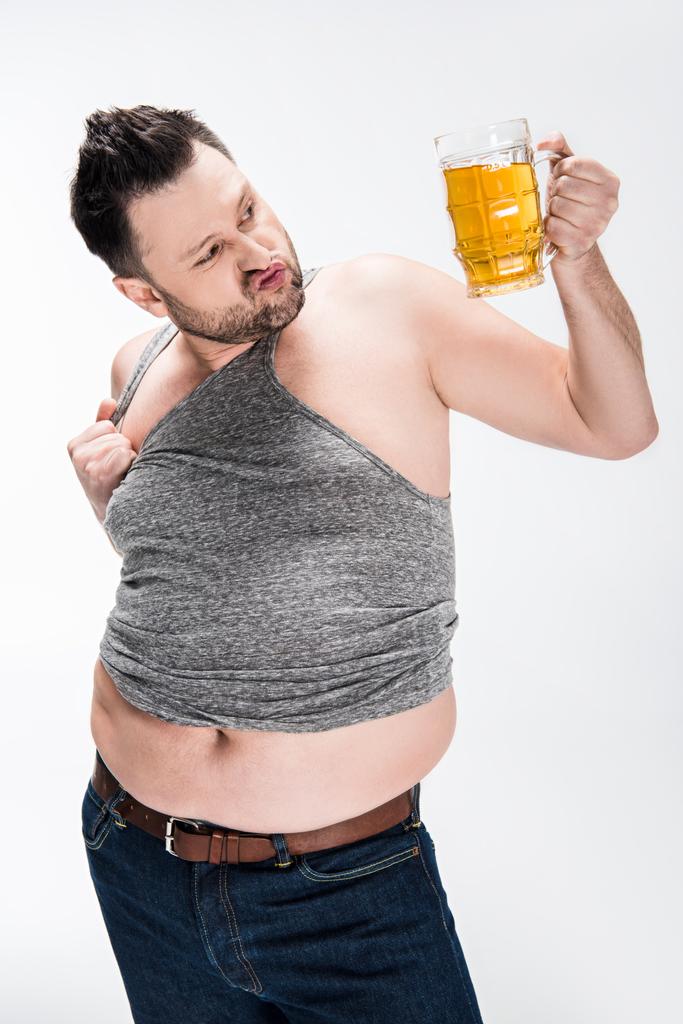 太り過ぎの男が唇をすりむき、白に隔離されたビールのグラスを保持 - 写真・画像