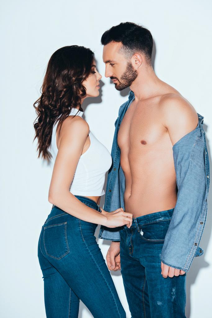 sensual jovem mulher descompactando jeans no namorado no cinza
 - Foto, Imagem