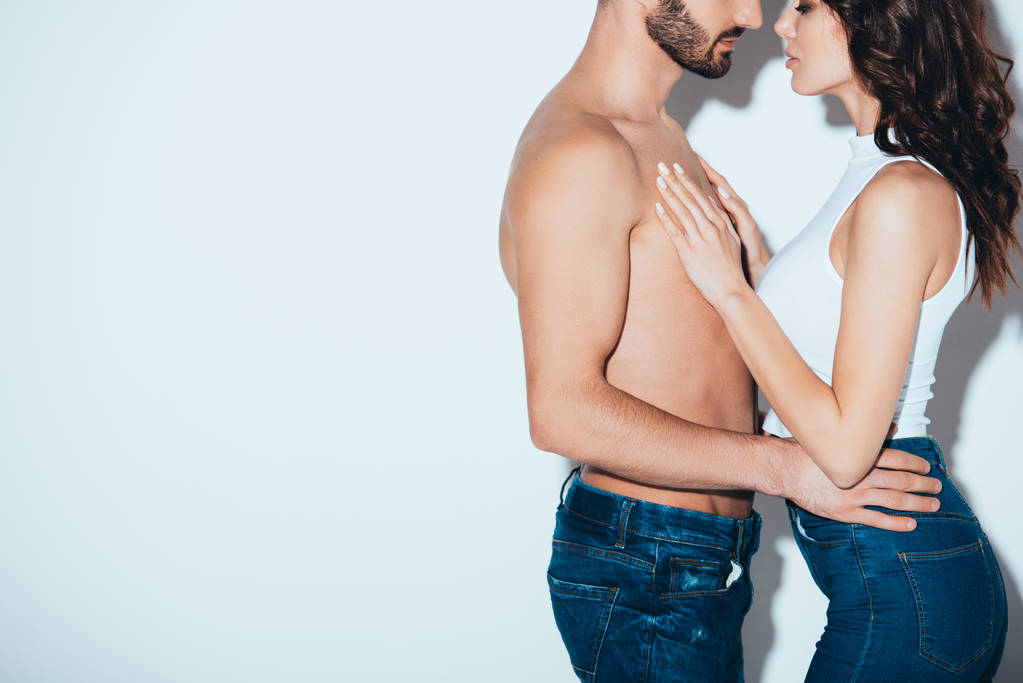 cropped view of couple in jeans embracing on grey - Photo, Image