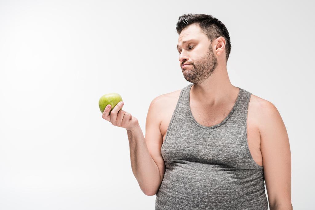 hombre con sobrepeso insatisfecho sosteniendo manzana verde aislada en blanco con espacio de copia
 - Foto, Imagen