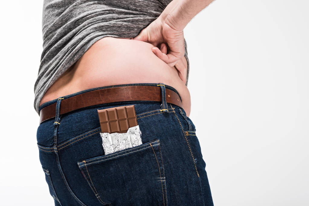 Teilansicht eines übergewichtigen Mannes mit Schokoriegel in der Tasche isoliert auf Weiß - Foto, Bild