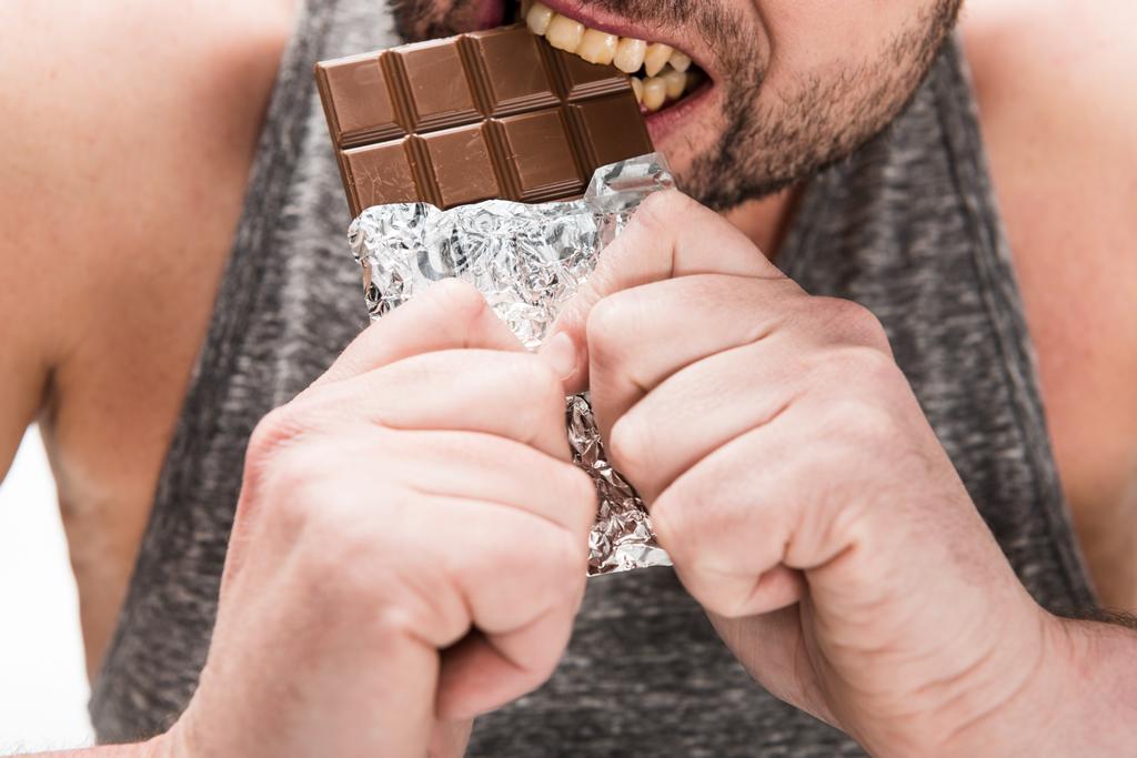 beyaz izole çikolata yiyen tombul adam kırpılmış görünümü - Fotoğraf, Görsel
