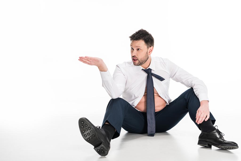 Übergewichtiger Mann in enger formaler Kleidung gestikuliert mit der Hand, während er auf Weiß mit Kopierraum sitzt - Foto, Bild